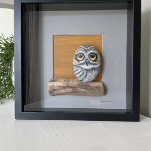 Handgemaakt kunstwerk van beschilderde uil op grote pebblestone zittend op drijfhout.