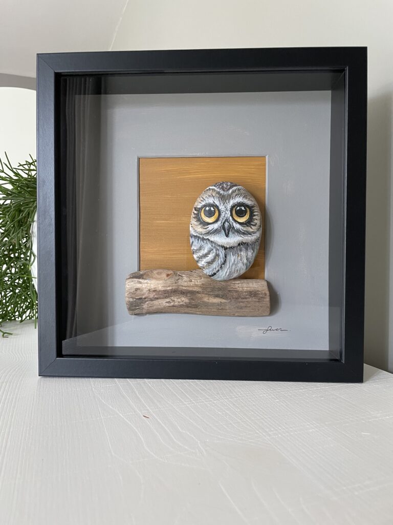 Handgemaakt kunstwerk van beschilderde uil op grote pebblestone zittend op drijfhout.