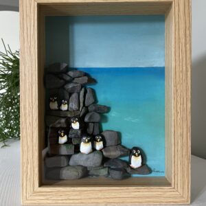 Ingelijst kunstwerk met handbeschilderde pebblestones als pinguïns op rotsen en zee van acrylverf