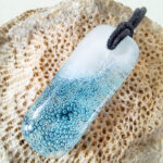 Gesmolten glazen hanger met aqua blauw zeegezicht, kustlijn. Met zwarte ketting
