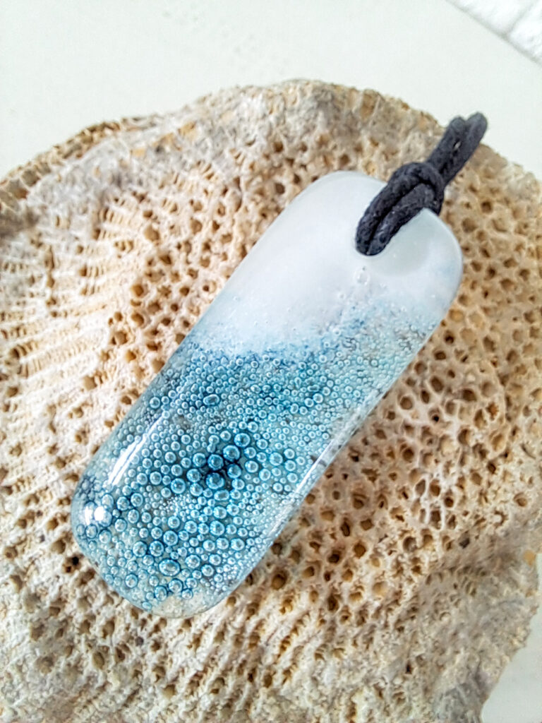 Gesmolten glazen hanger met aqua blauw zeegezicht, kustlijn. Met zwarte ketting