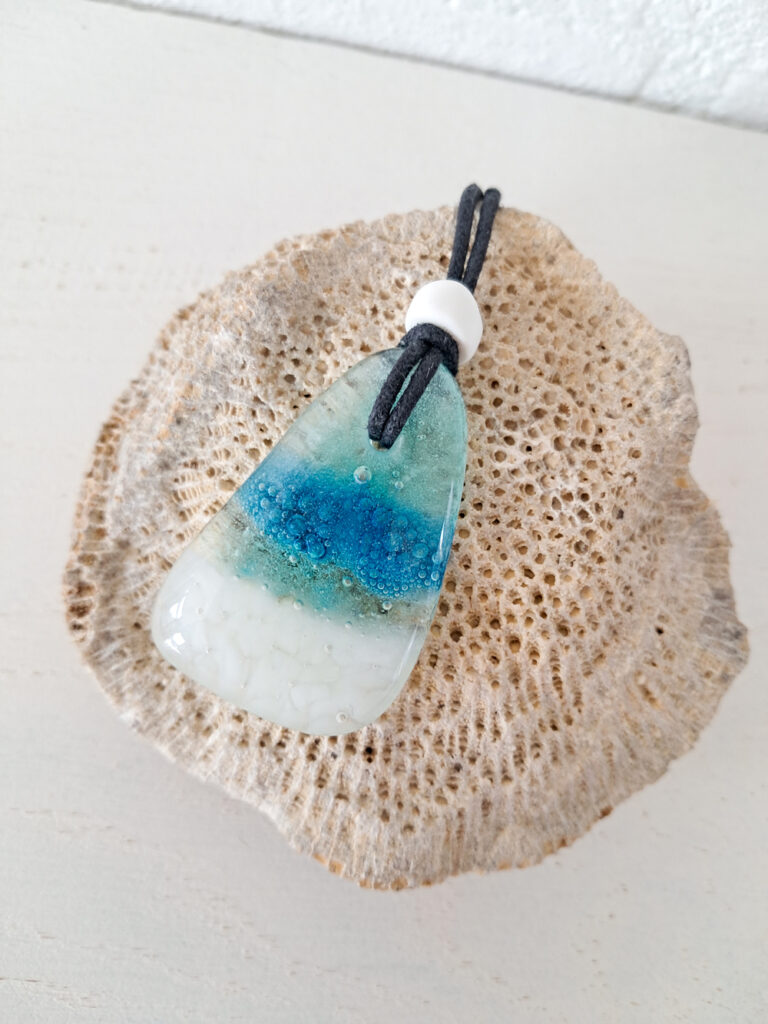 Gesmolten glazen hanger met zeegezicht en handelskraal met zwarte ketting